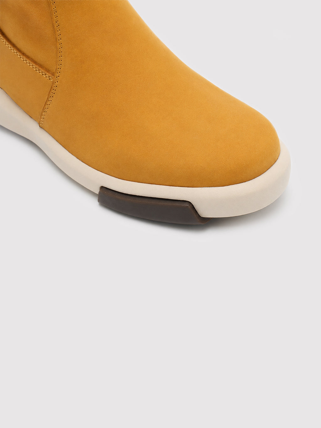 Close-up of the yellow suede toe and stitching above a cream sole with a dark brown tread detail.