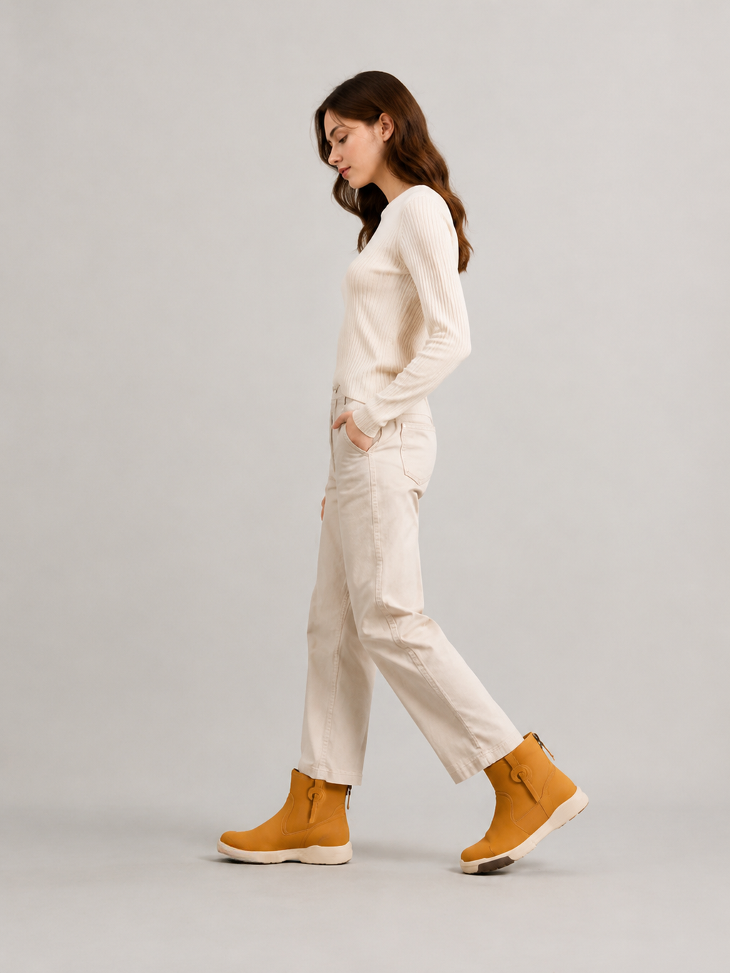 Model walking in yellow suede ankle boots, styled with a cream sweater and cropped cream trousers.