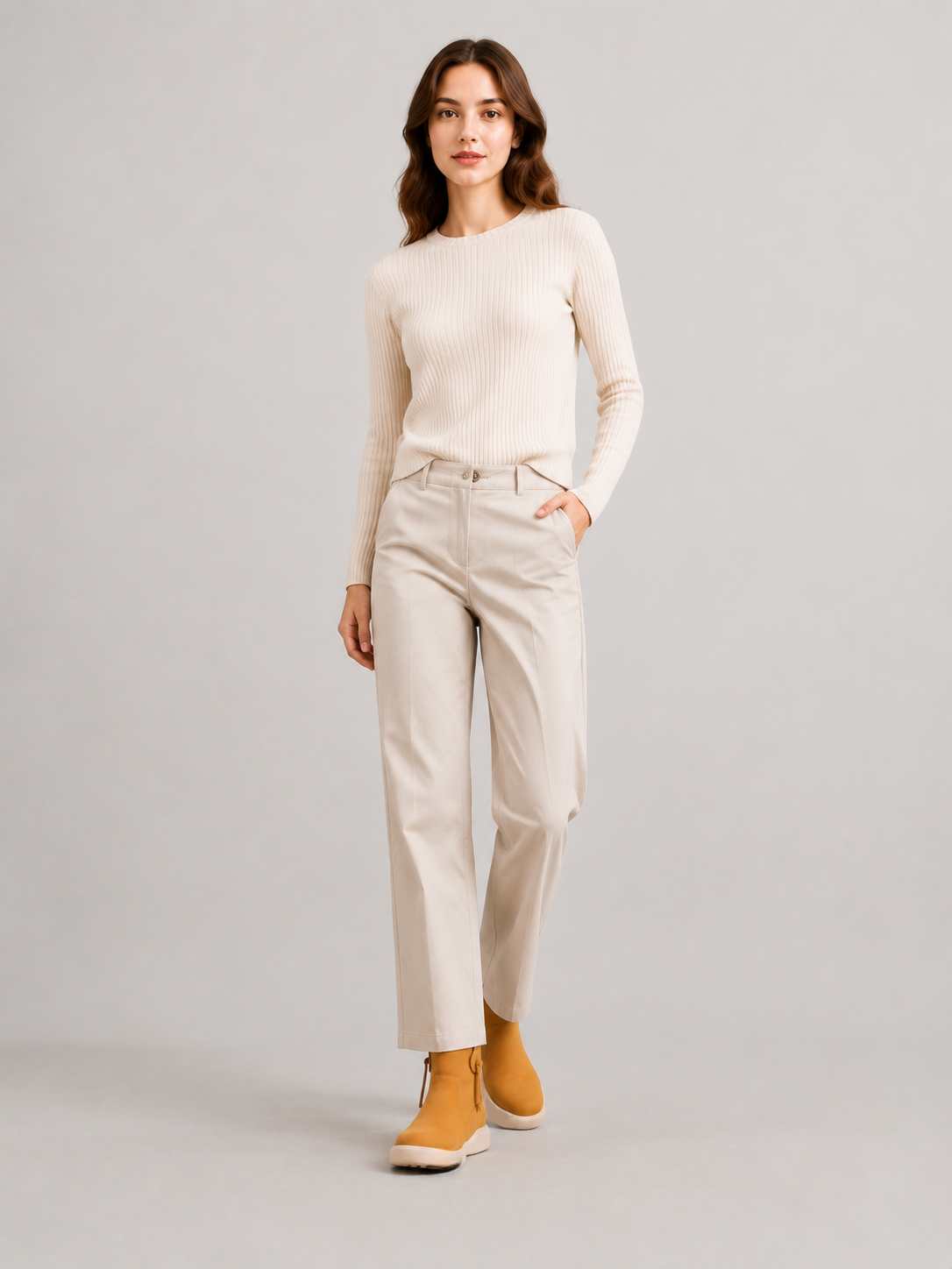 Front studio view of a model wearing yellow suede ankle boots with a fitted cream sweater and ivory trousers.